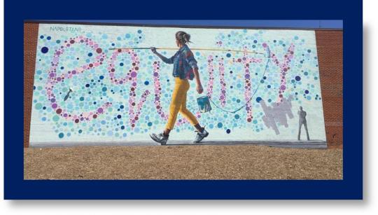 Female painter in front of an equity mural